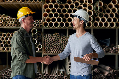 Buy stock photo Cropped shot of two male construction workers shaking hands while standing in an industrial warehouse
