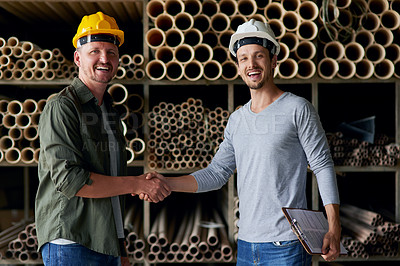Buy stock photo Cropped portrait of two male construction workers shaking hands while standing in an industrial warehouse