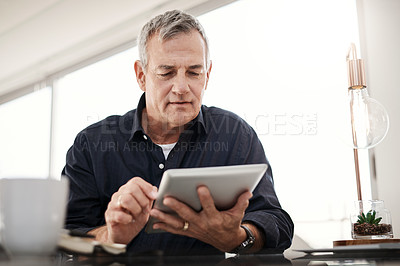 Buy stock photo Shot of a mature man working on a digital tablet at home