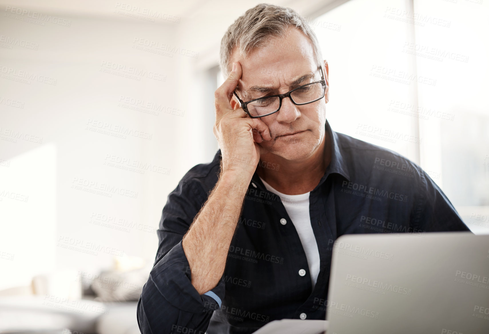 Buy stock photo Shot of a mature man looking stressed out while working on a laptop at home