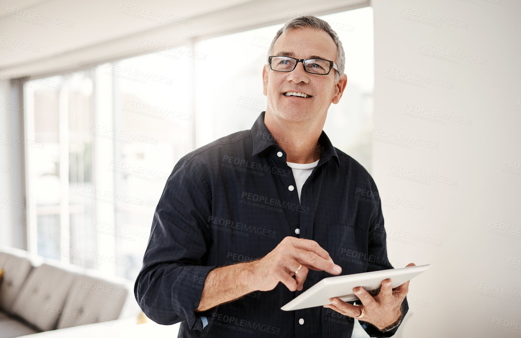 Buy stock photo Shot of a mature man using a digital tablet at home