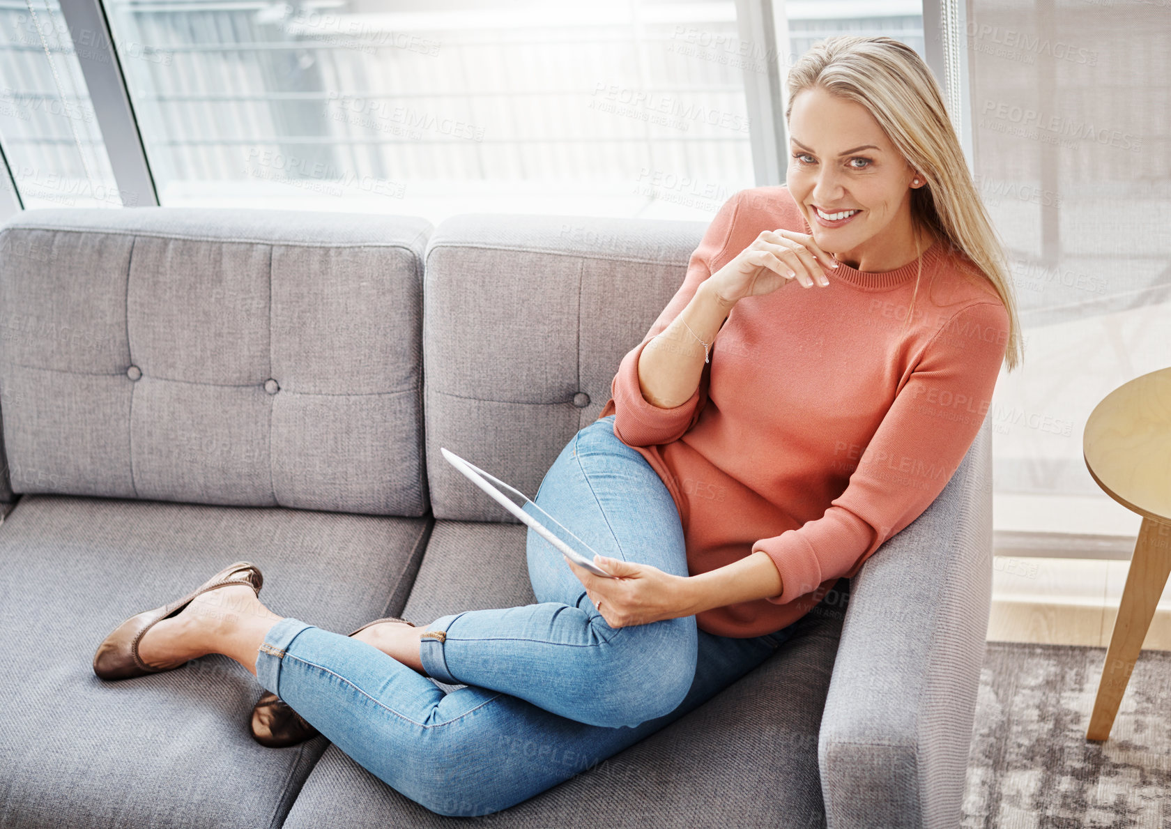 Buy stock photo Portrait of an attractive mature woman using a digital tablet while relaxing on the sofa at home