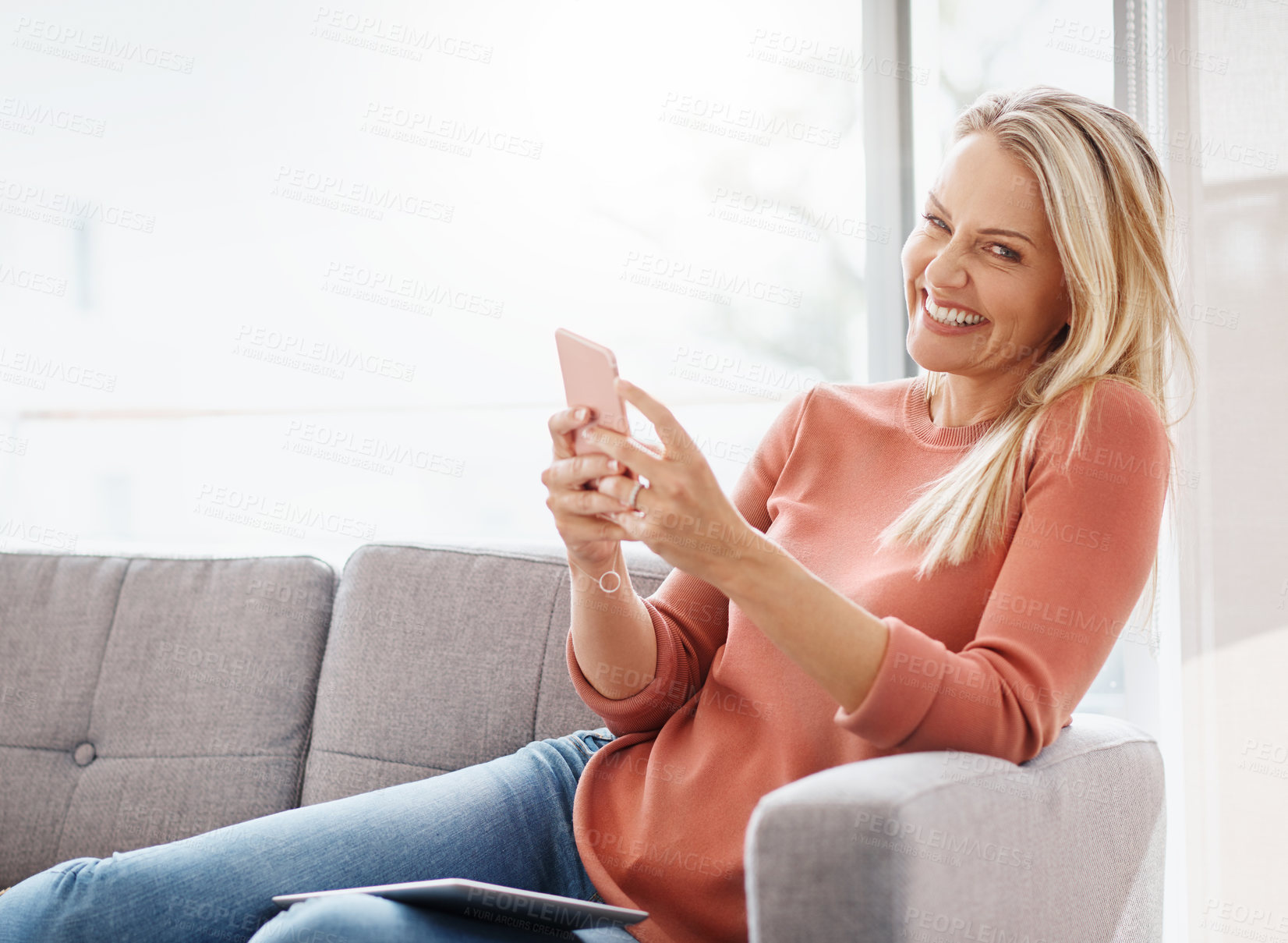 Buy stock photo Portrait of an attractive mature woman using a mobile phone while relaxing on the sofa at home