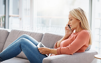 Buy stock photo Shot of an attractive mature woman using a mobile phone and digital tablet while relaxing on the sofa at home