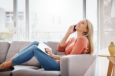 Buy stock photo Shot of an attractive mature woman using a mobile phone and digital tablet while relaxing on the sofa at home