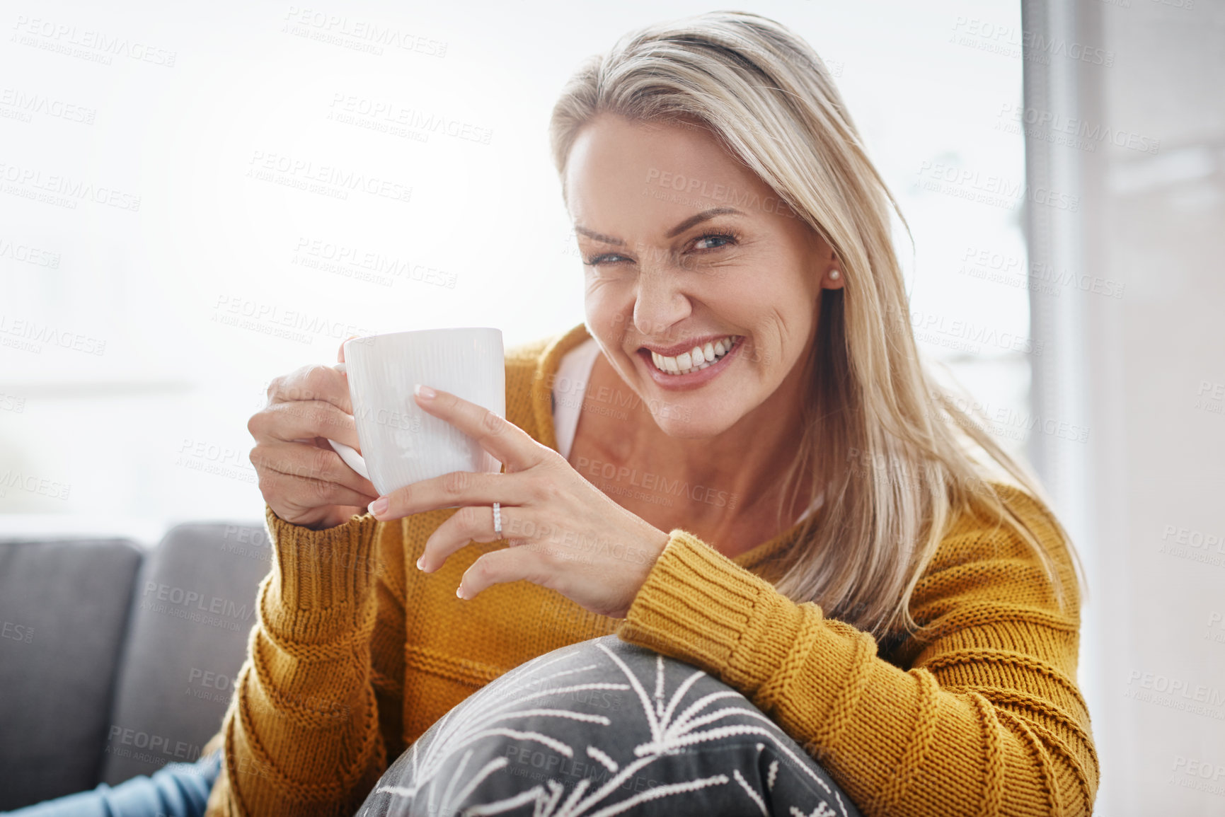 Buy stock photo Portrait of an attractive mature woman enjoying a beverage while relaxing on the sofa at home