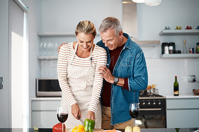Buy stock photo Shot of a man standing behind his wife while she prepares a meal