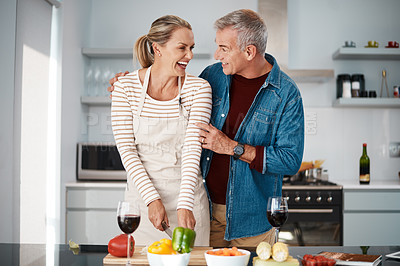 Buy stock photo Shot of a man standing behind his wife while she prepares a meal