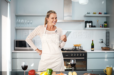 Buy stock photo Shot of a mature woman using her digital tablet while wearing her apron in the kitchen