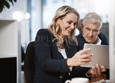 Buy stock photo Shot of two businesspeople using a digital tablet in an office