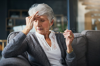 Buy stock photo Shot of a senior woman suffering from a headache at home