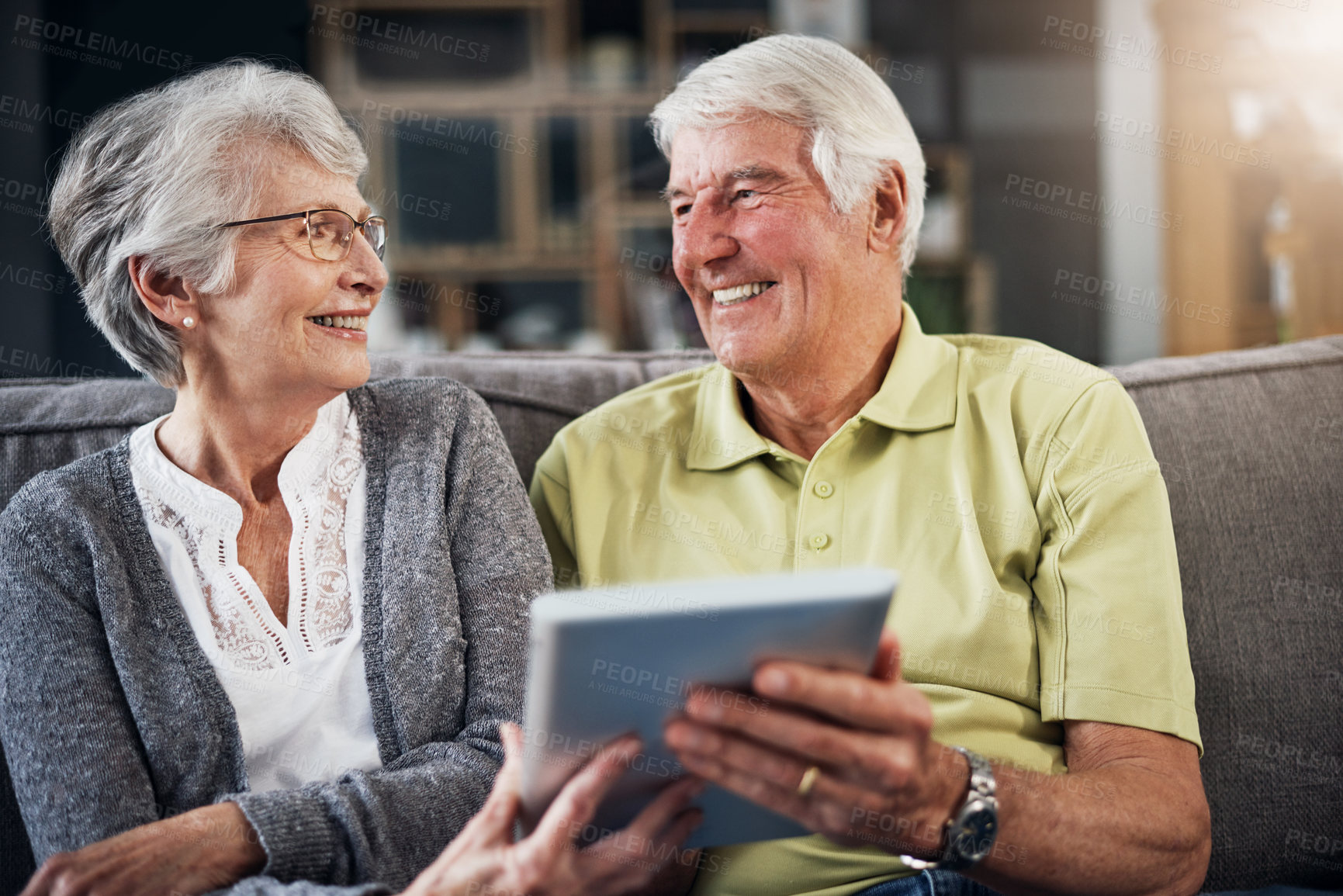 Buy stock photo Shot of a senior couple using a digital tablet together on the sofa at home