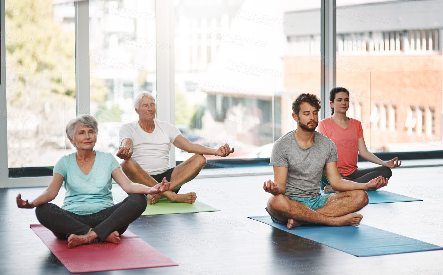 Buy stock photo Full length shot of a group of people meditating while practicing yoga