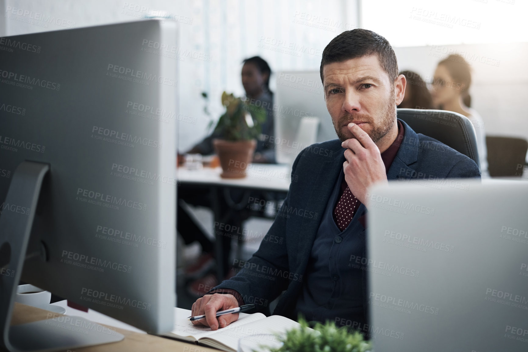 Buy stock photo Shot of a mature businessman using a computer at his desk in a modern office