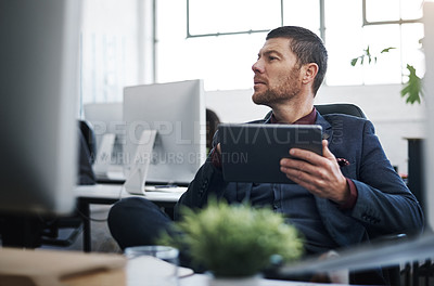 Buy stock photo Shot of a mature businessman using a digital tablet at his desk in a modern office