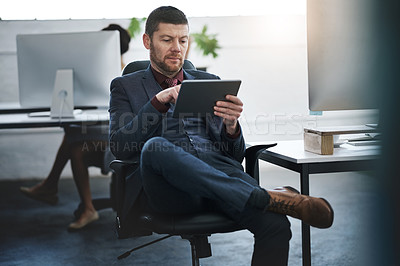 Buy stock photo Shot of a mature businessman using a digital tablet in a modern office