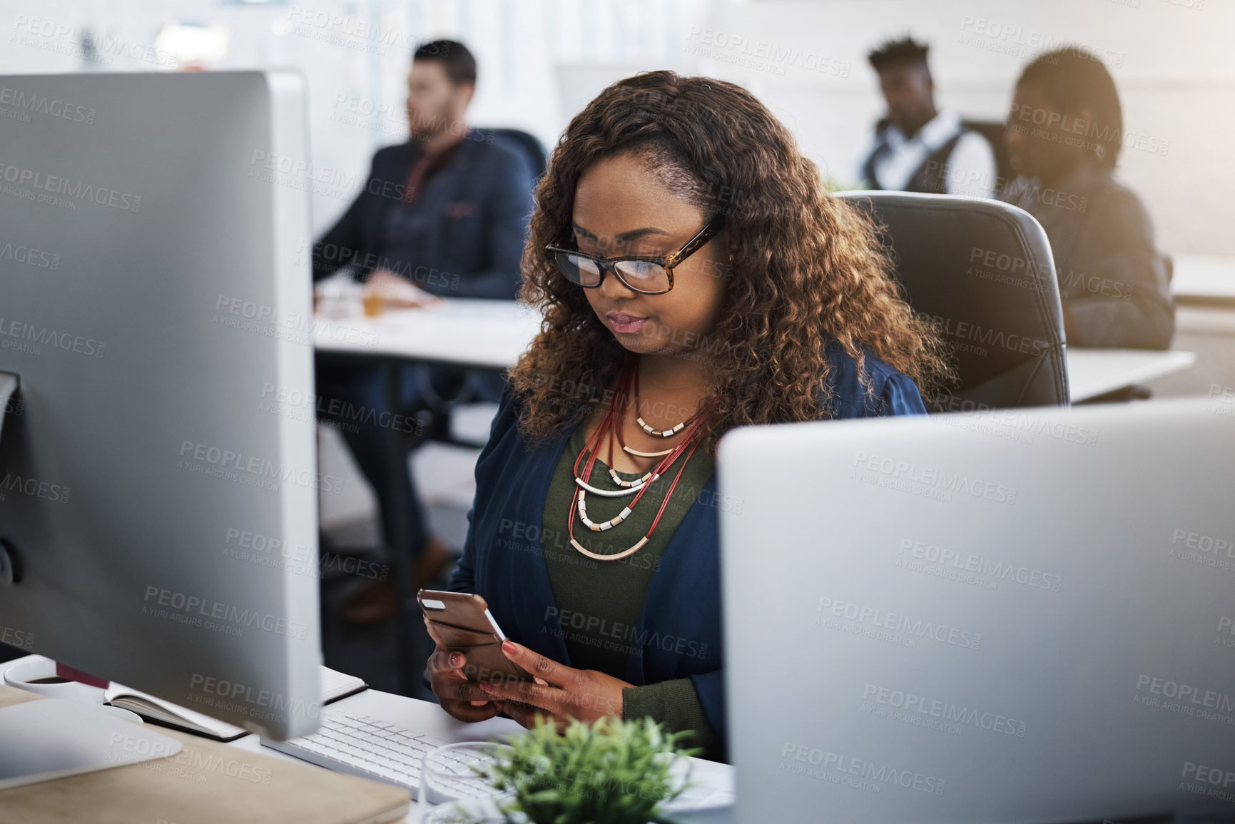 Buy stock photo Shot of a young businesswoman using a mobile phone at her desk in a modern office