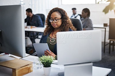 Buy stock photo Shot of a young businesswoman using a digital tablet at her desk in a modern office