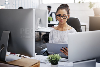Buy stock photo Shot of a young businesswoman using a digital tablet at her desk in a modern office