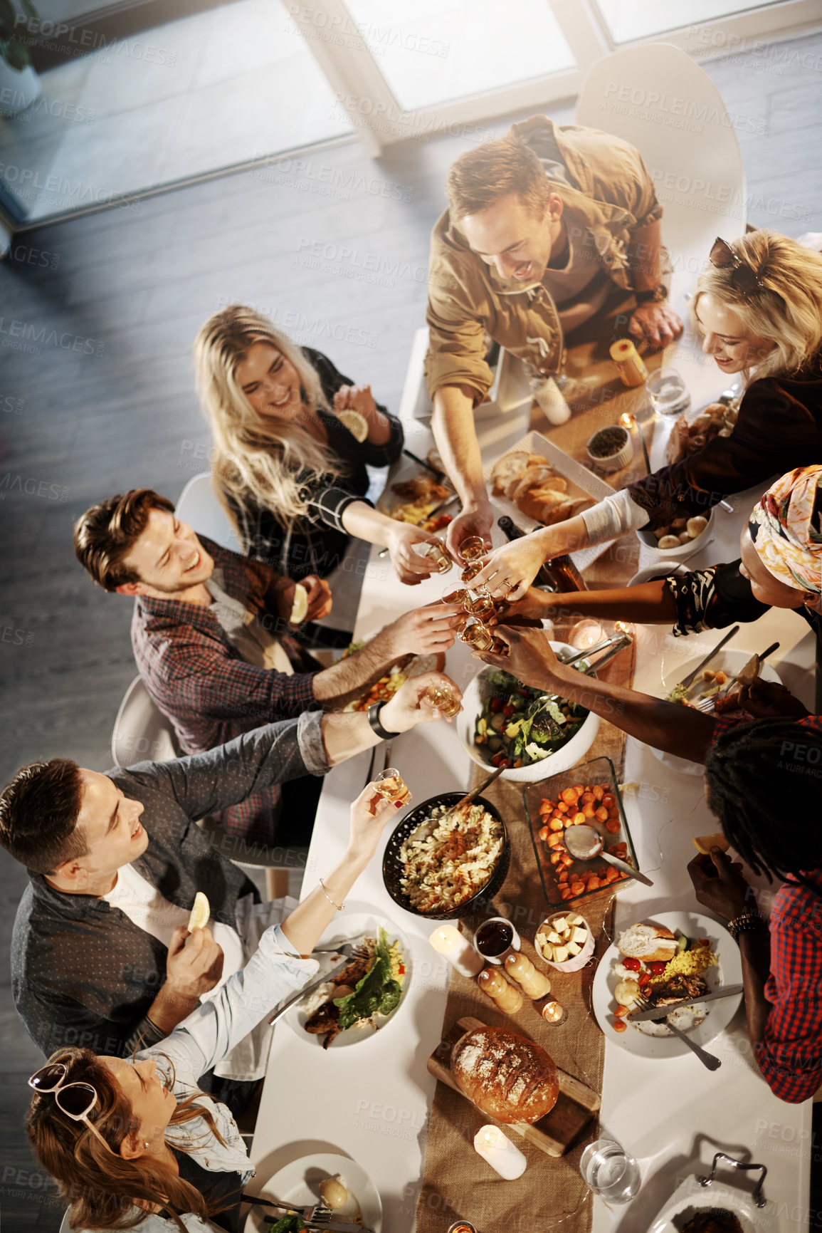 Buy stock photo Shot of a group of young friends making a toast at a dinner party