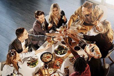 Buy stock photo Shot of a group of young friends making a toast at a dinner party