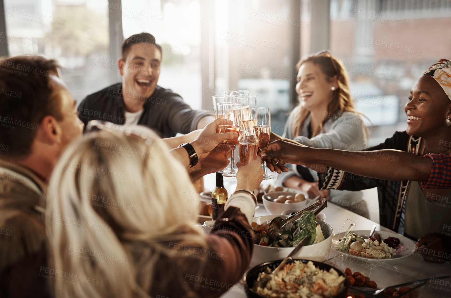 Buy stock photo Shot of a group of young friends making a toast at a dinner party