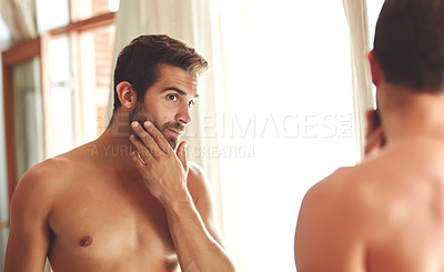 Buy stock photo Cropped shot of a shirtless young man checking out his skin in the bathroom mirror
