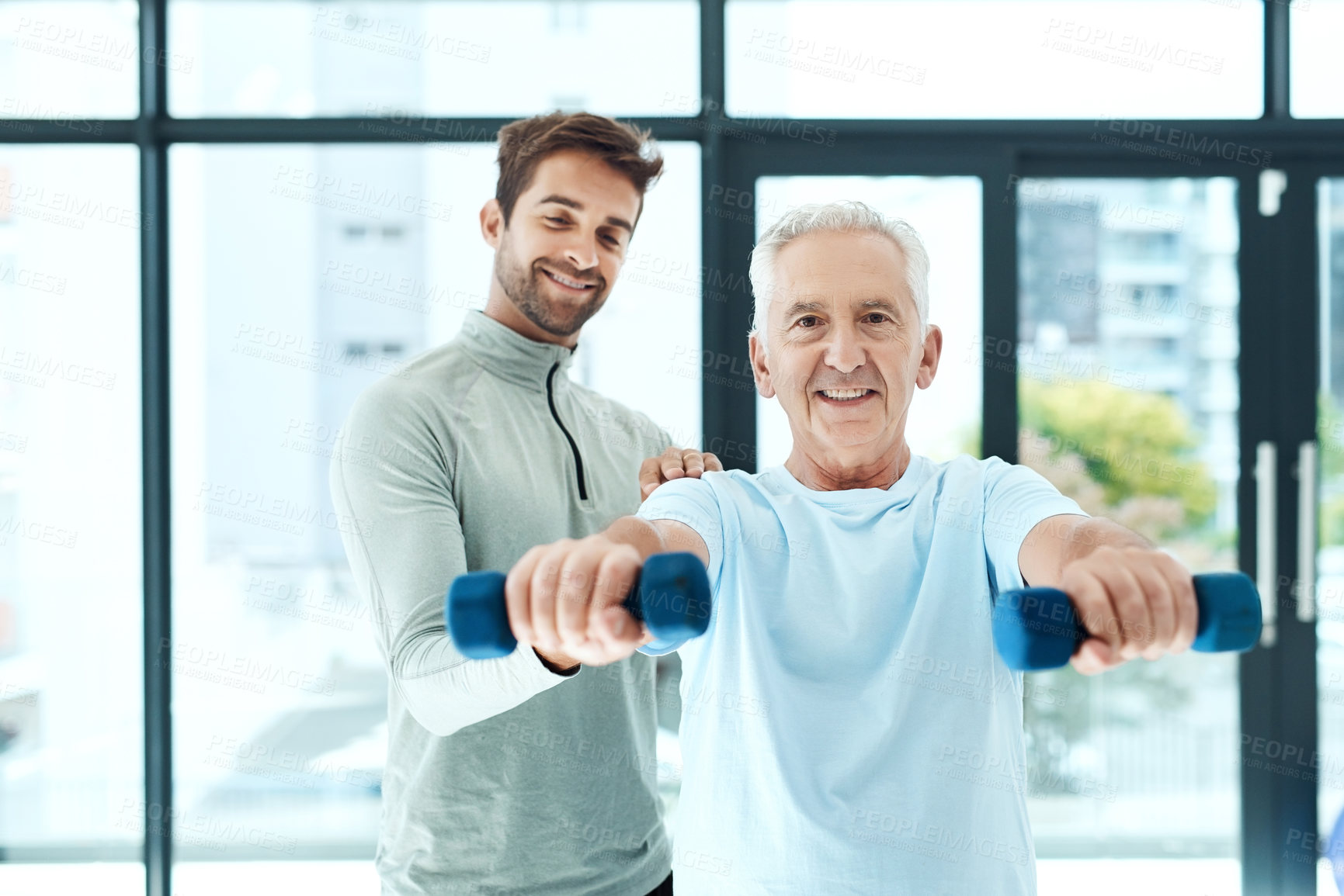 Buy stock photo Shot of a friendly physiotherapist helping his senior patient work out with weights