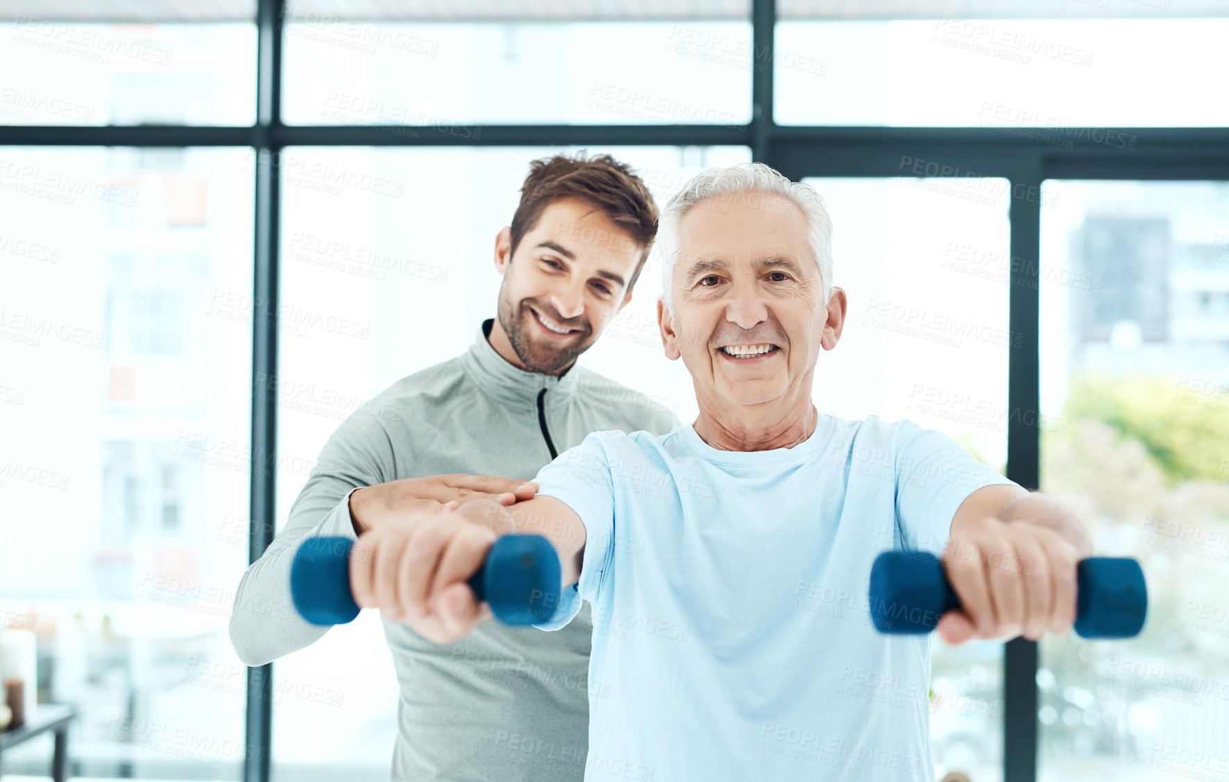 Buy stock photo Shot of a friendly physiotherapist helping his senior patient work out with weights