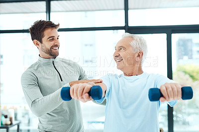 Buy stock photo Shot of a friendly physiotherapist helping his senior patient work out with weights