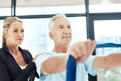 Buy stock photo Shot of a a physiotherapist working with a senior patient using a resistance band