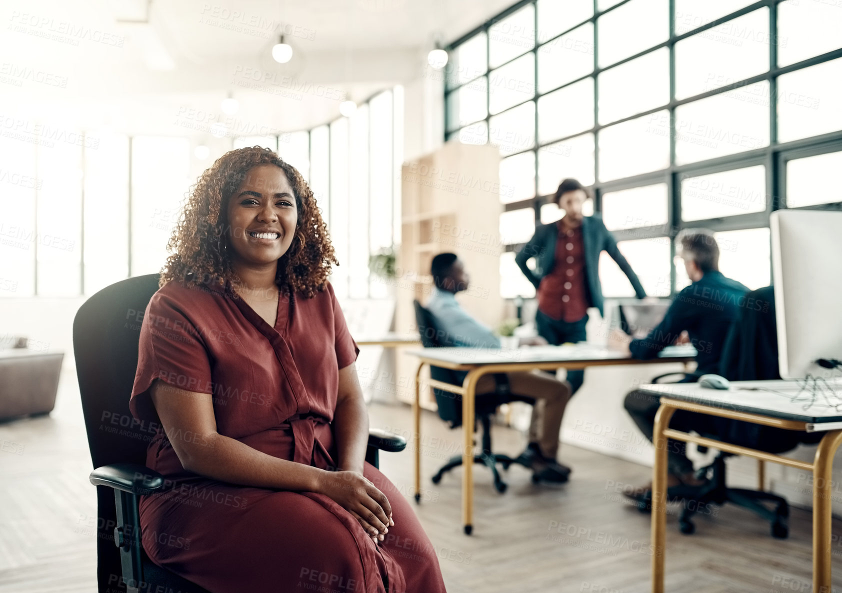 Buy stock photo Portrait of a young businesswoman sitting in a modern office with her colleagues working in the background