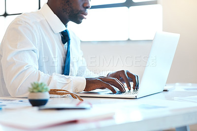 Buy stock photo Shot of an unrecognizable businessman typing on his laptop while being seated at a desk in the office during the day