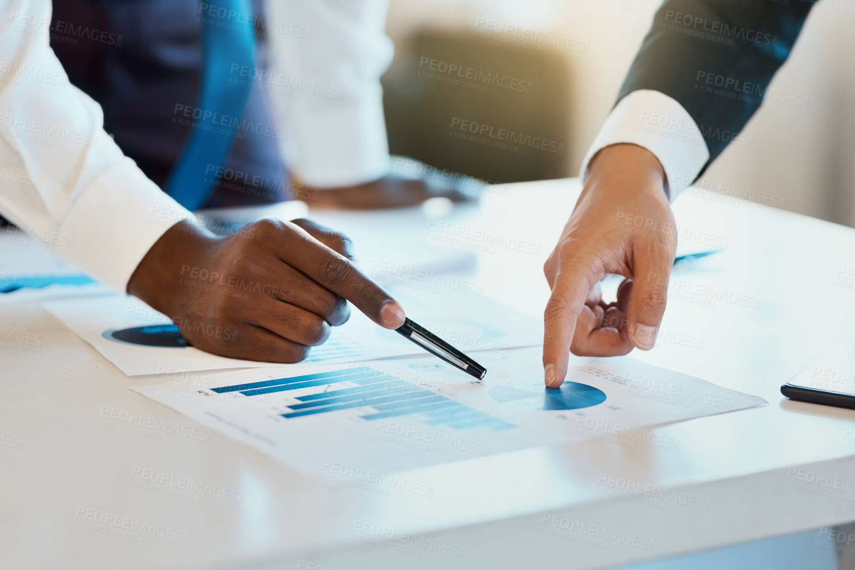 Buy stock photo Closeup of two unrecognizable businesspeople making notes while looking at graphs in the office at work during the day