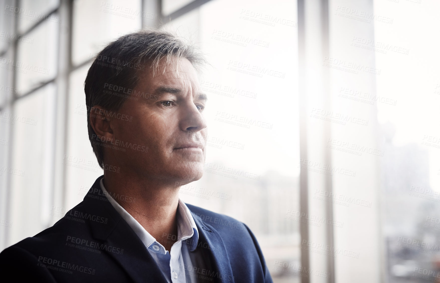 Buy stock photo Shot of a mature businessman looking out a window in an office