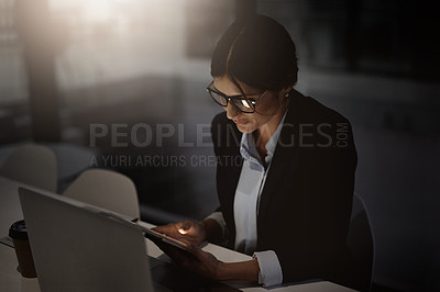 Buy stock photo Shot of a young businesswoman using a digital tablet and laptop during a late at night in a modern office