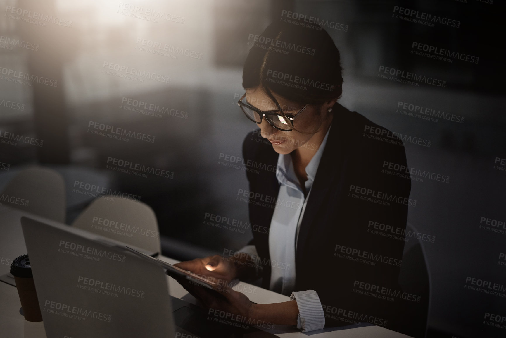 Buy stock photo Shot of a young businesswoman using a digital tablet and laptop during a late at night in a modern office