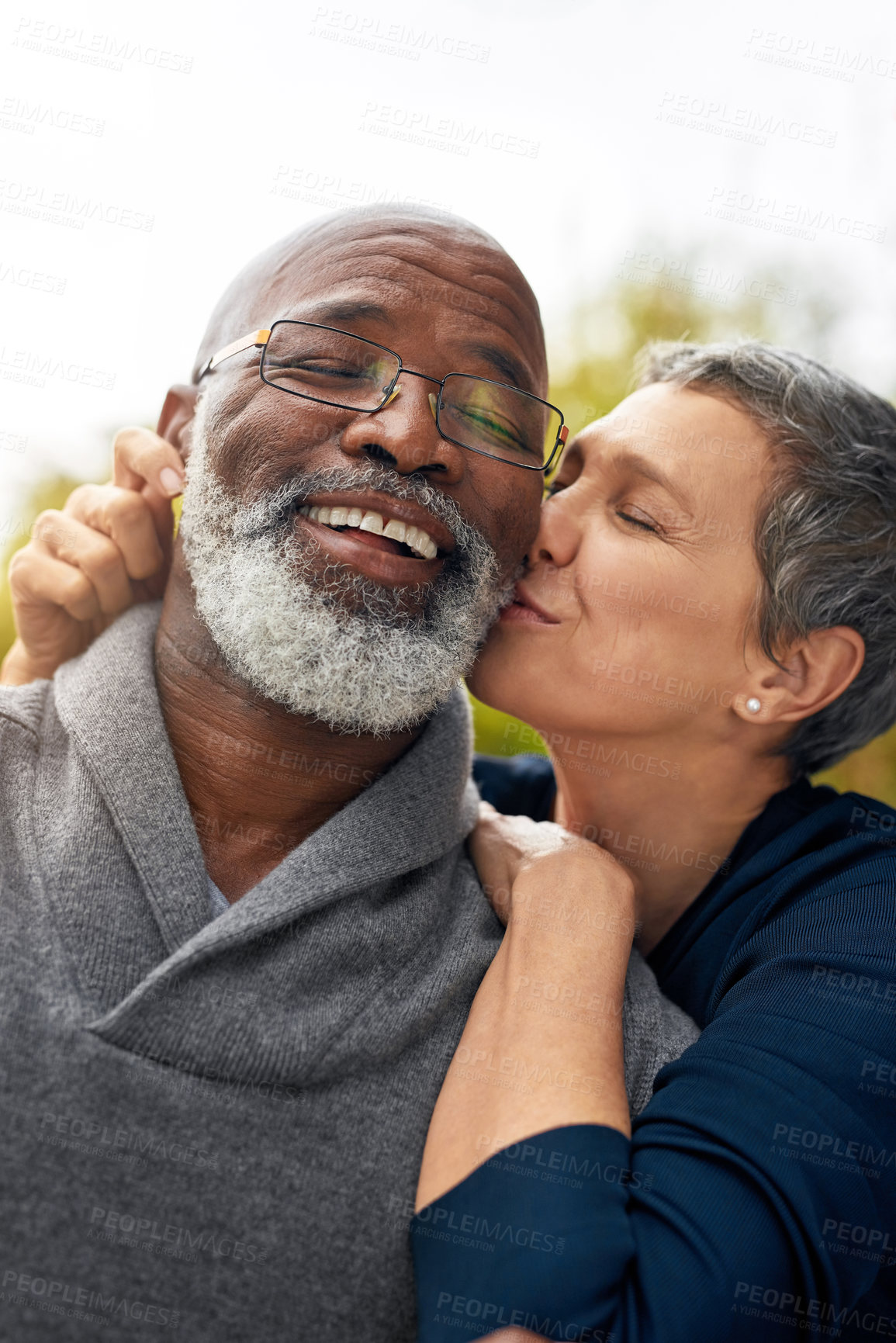 Buy stock photo Interracial senior couple, kiss and relax in park, garden or nature for kiss or care together. Happy man, woman and partner for retirement, love and support for marriage and vacation for pensioner