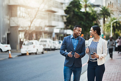 Buy stock photo Shot of two businesspeople having a discussion while walking in the city