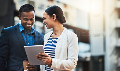 Buy stock photo Shot of two businesspeople using a digital tablet in the city