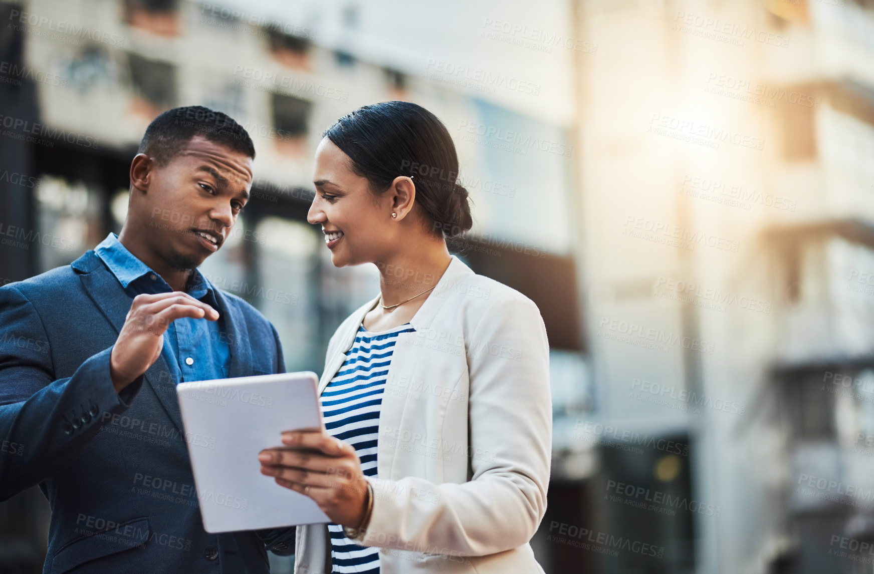 Buy stock photo Shot of two businesspeople using a digital tablet in the city