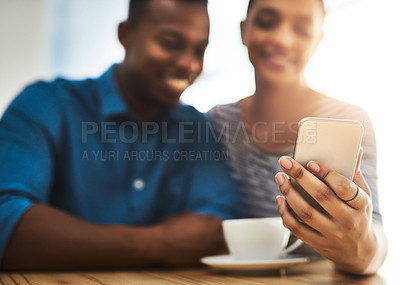 Buy stock photo Shot of a young man and woman using a mobile phone together on a date at a coffee shop