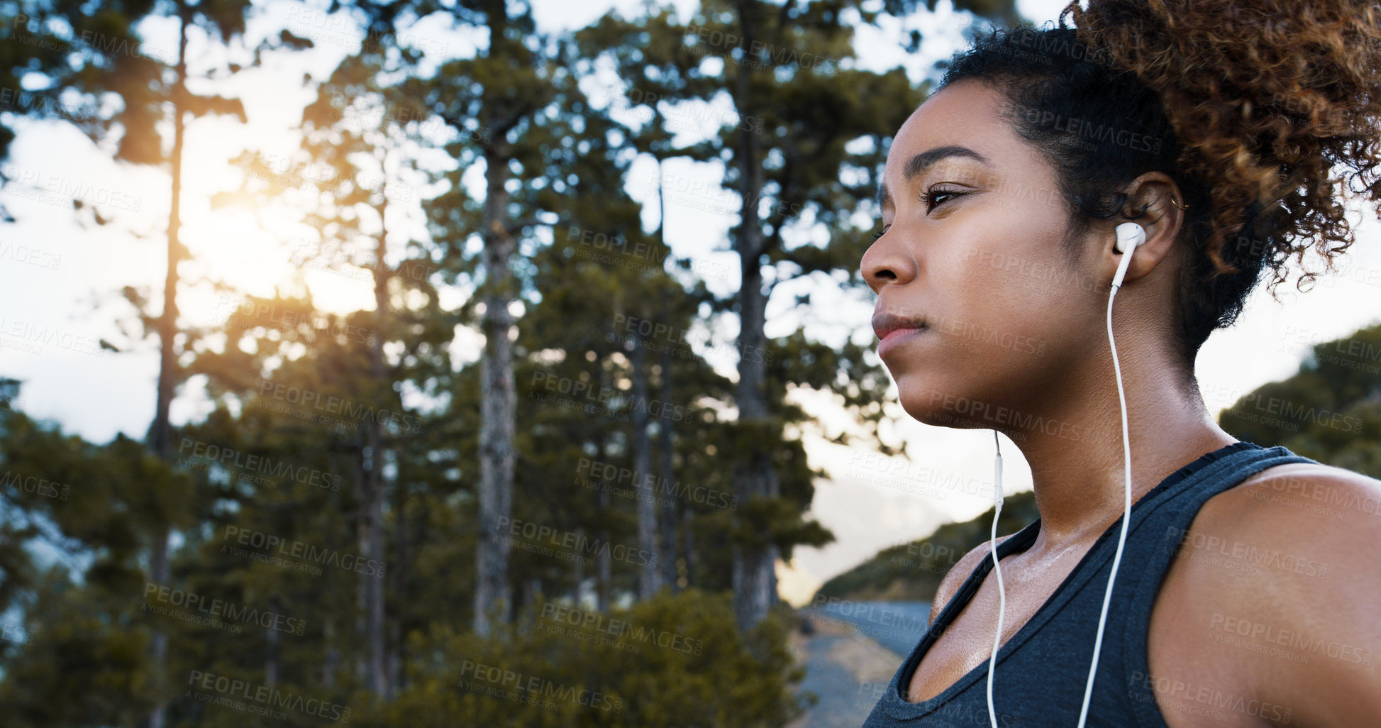 Buy stock photo Shot of a sporty young woman listening to music while exercising outdoors