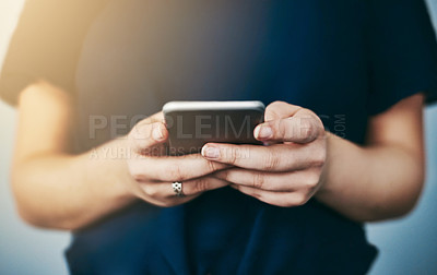 Buy stock photo Studio shot of an unrecognizable young woman using her cellphone against a grey background