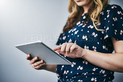 Buy stock photo Studio shot of an unrecognizable young woman using her digital tablet against a grey background