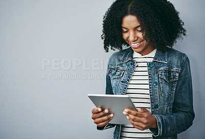 Buy stock photo Studio shot of an attractive young woman using her digital tablet against a grey background
