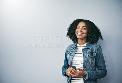 Buy stock photo Studio portrait of an attractive young woman using her cellphone against a grey background