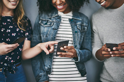 Buy stock photo Studio shot of three unrecognizable young people using their cellphones against a grey background