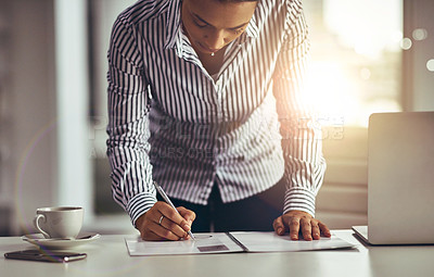 Buy stock photo Shot of a young businesswoman writing notes on a document in an office