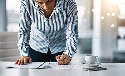 Buy stock photo Shot of a young businesswoman writing notes on a document in an office